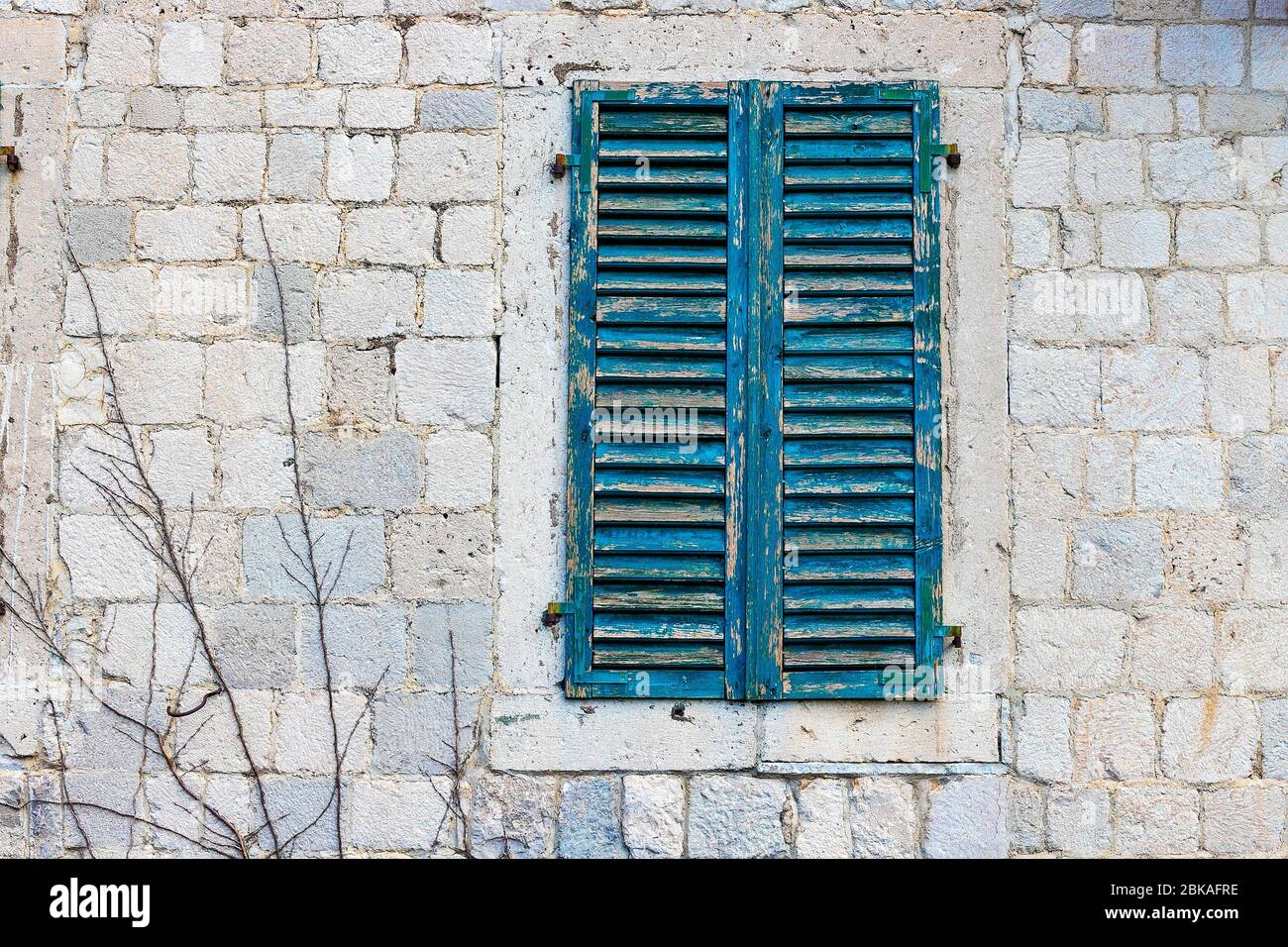 Autentica casa con un muro di pietra, con belle vecchie finestre aperte e con persiane verdi, e con vasi sulla finestra. Montenegro Foto Stock