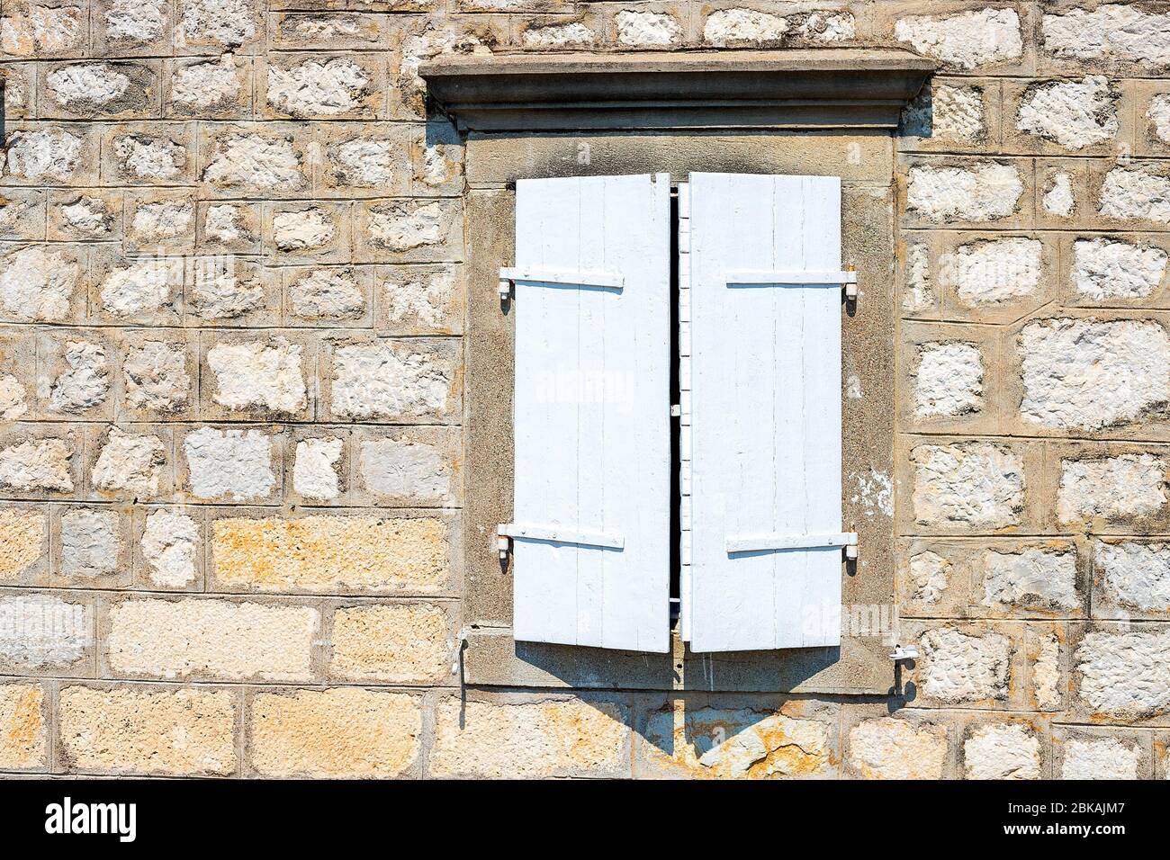 Una casa autentica con un muro di pietra, con belle vecchie finestre e con persiane bianche e marroni, e una vecchia lanterna. Montenegro Foto Stock