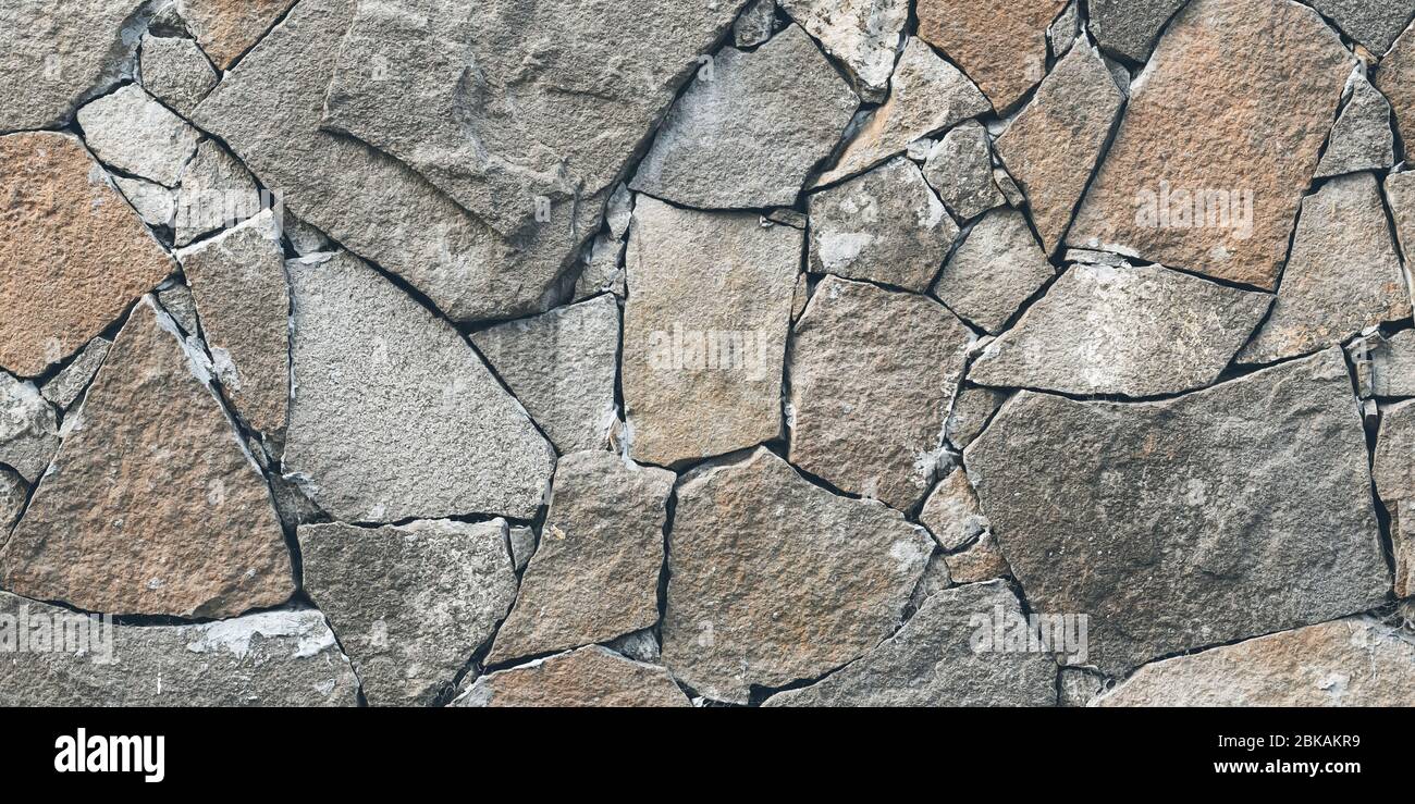Struttura rocciosa, parete di fondo in pietra. Mosaico di vecchie pietre grigie sul pavimento. Ampio panorama, banner panoramico. Facciata grunge architettura, piastrella fr Foto Stock