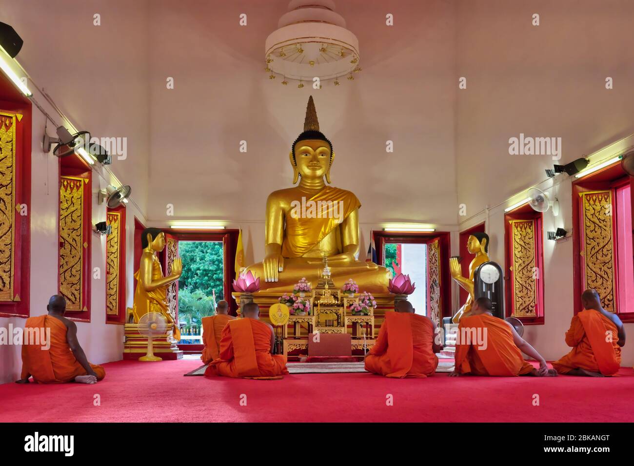 I monaci buddisti con ruggito arancione si sono riuniti per le preghiere serali di fronte alla statua del Buddha di Wat Mongkon Nimit, Phuket, Thailandia Foto Stock