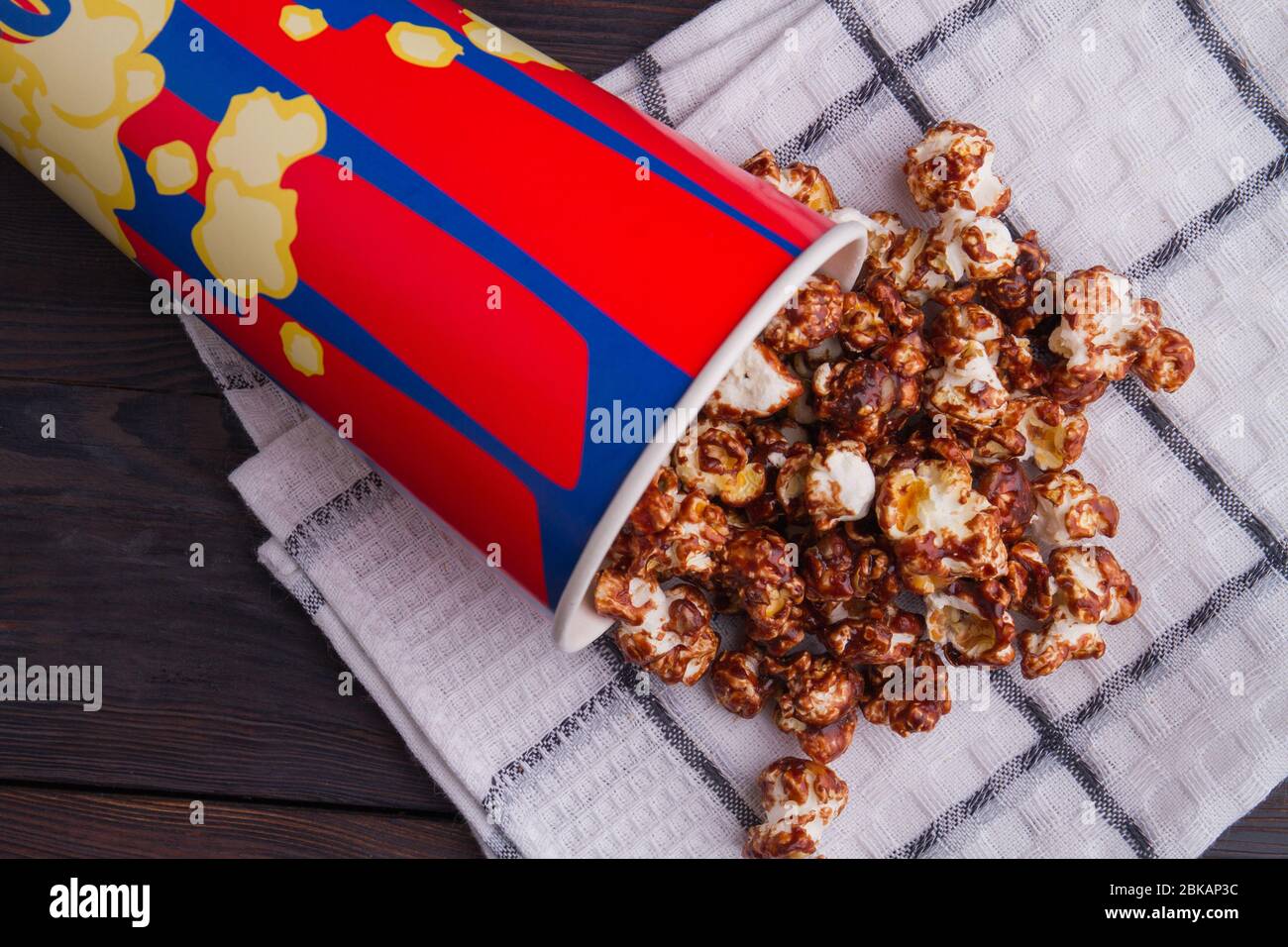 Primo piano popcorn di cioccolato sparso dal secchio su un asciugamano. Foto Stock