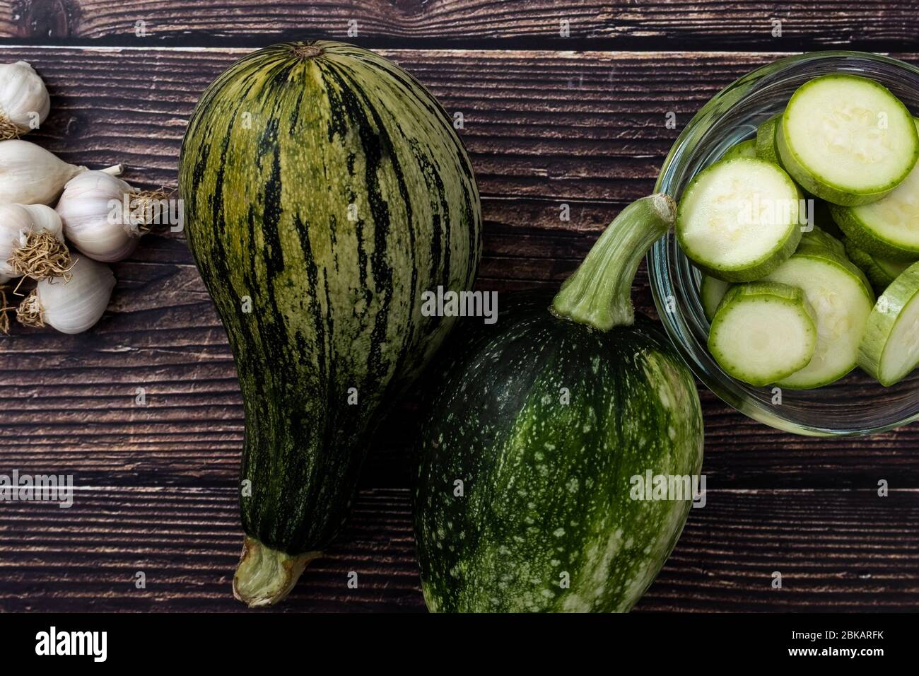 Vista dall'alto delle zucchine e delle zucchine a fette su sfondo di legno. Verdure fresche e biologiche da giardino. Foto Stock