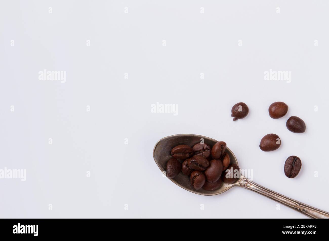 Cucchiaino da tè con chicchi di caffè su sfondo bianco. Foto Stock