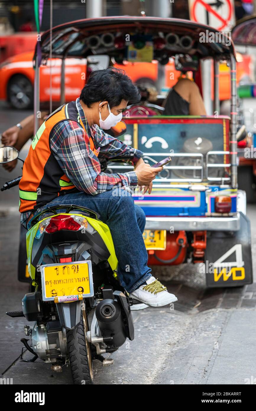 Moto tassista con maschera facciale e telefono cellulare durante Covid 19 pandemic, Bangkok, Thailandia Foto Stock