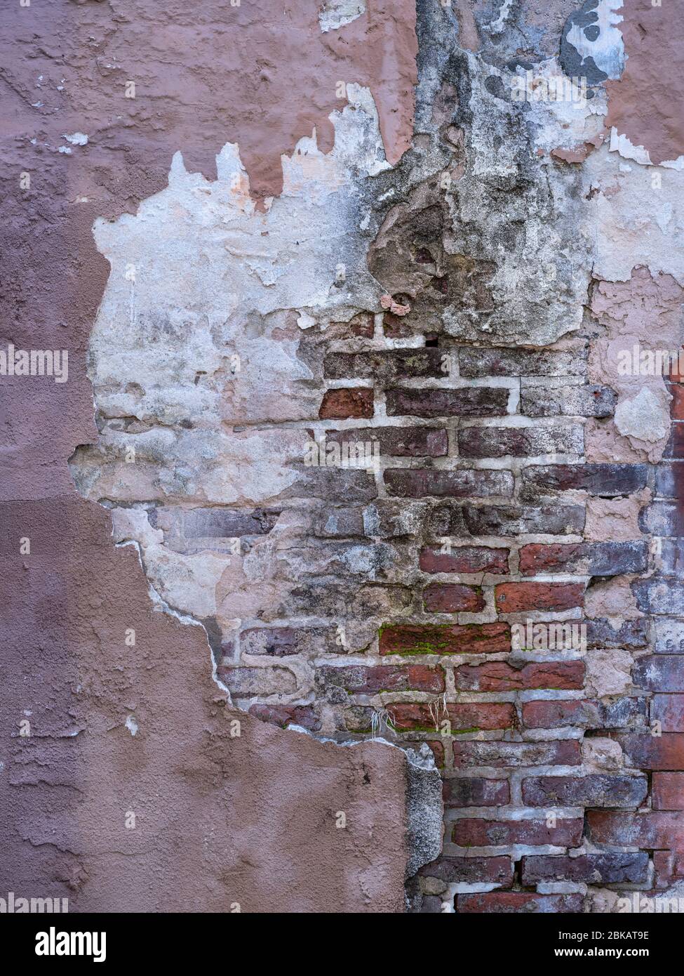 Vecchio muro con vernice di pelatura stucco mattoni esposti Foto Stock