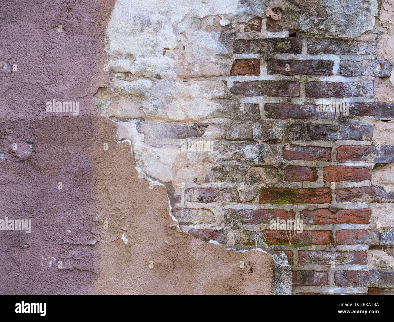 Vecchio muro con vernice di pelatura stucco mattoni esposti Foto Stock