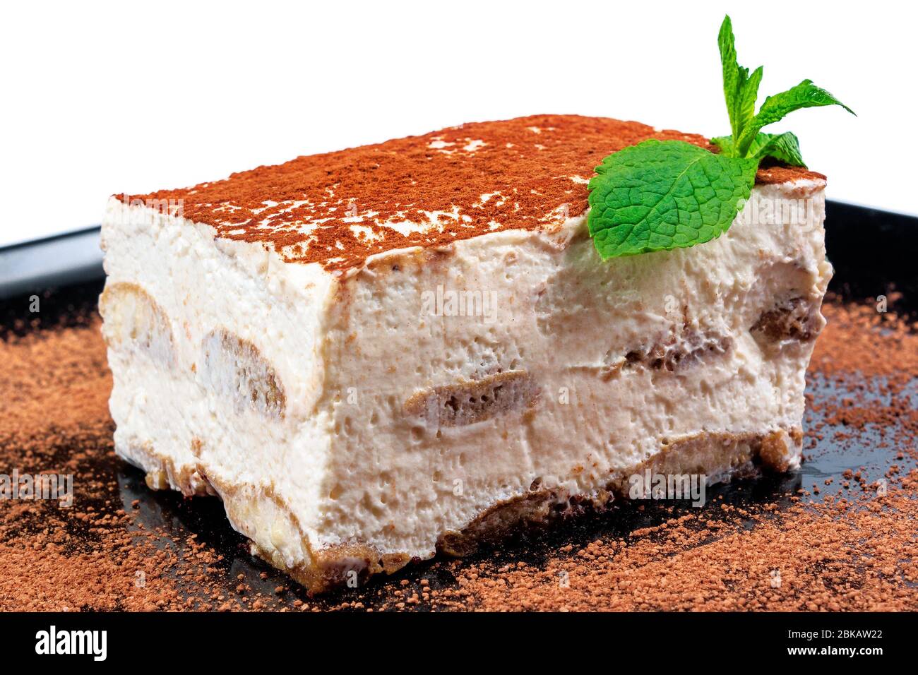 torta tiramisù su piatto nero. gustoso dessert italiano decorato con menta Foto Stock