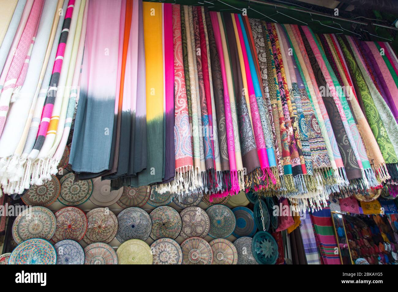 Scialli colorati appesi sul fronte del negozio nel souk di Marrakesh aka Djemaa el fna, Marrakech, Marocco, Nord Africa Foto Stock