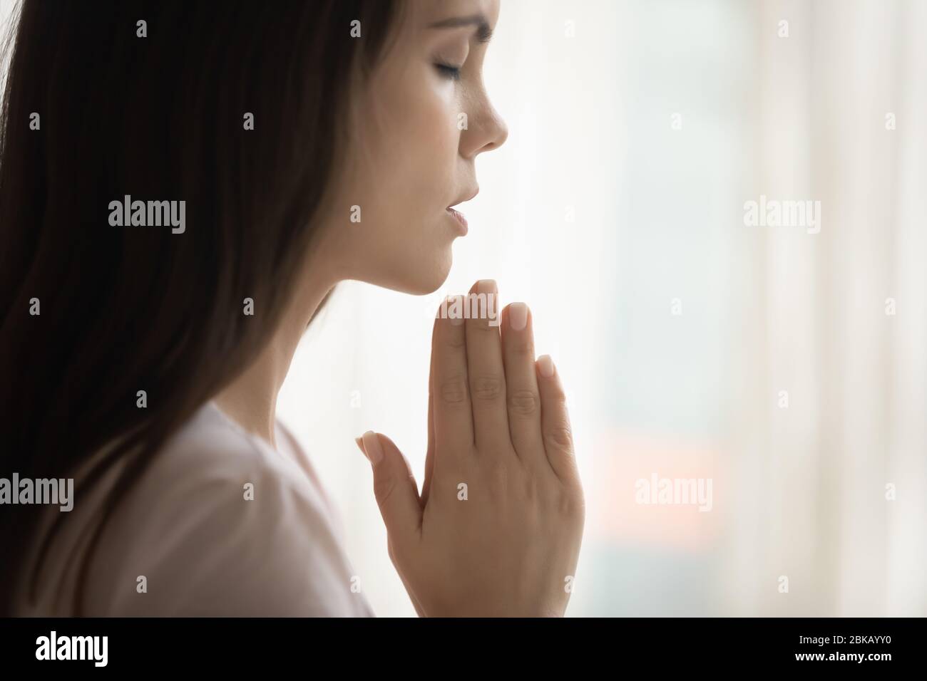 Donna giovane superstiziosa credente prega Dio a casa Foto Stock