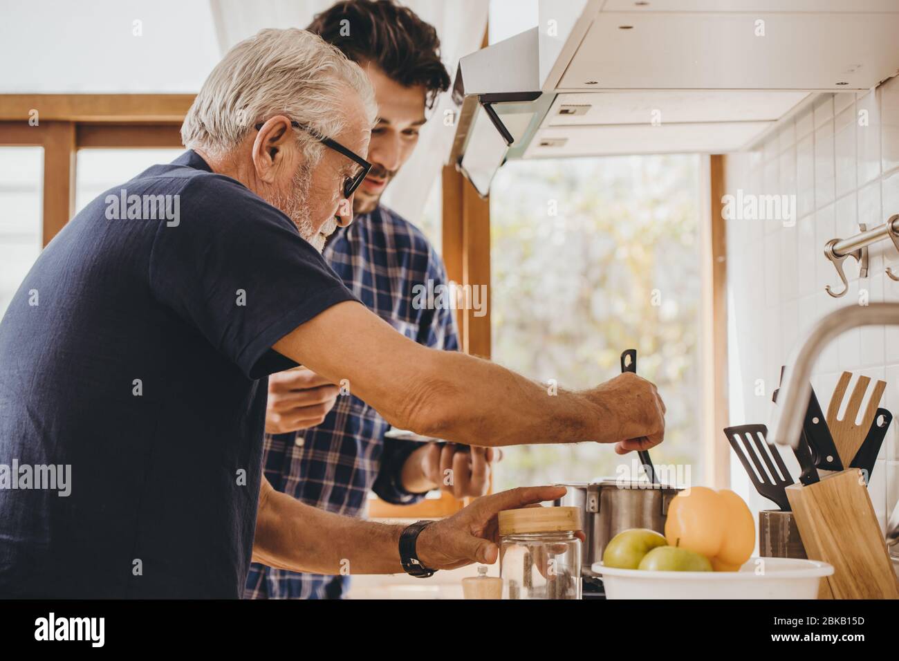 L'anziano che cucina in cucina con il suo figlio, l'uomo felice della famiglia momento buon mentore l'anziano cura dal figlio. Foto Stock