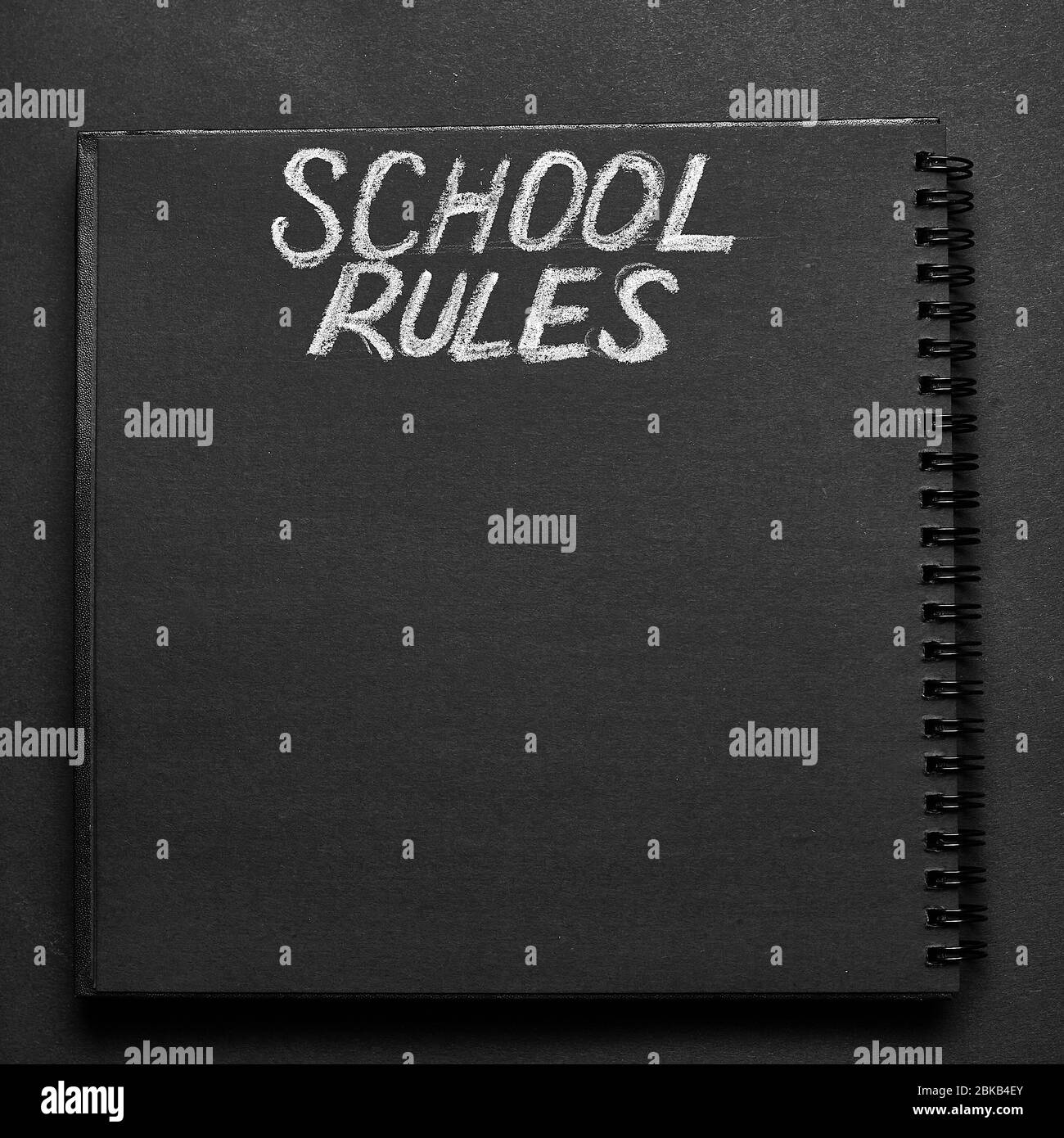 La scuola regola la parola scritta su un blocco note con spazio vuoto. Sfondo nero del blocco note vuoto. Foto Stock