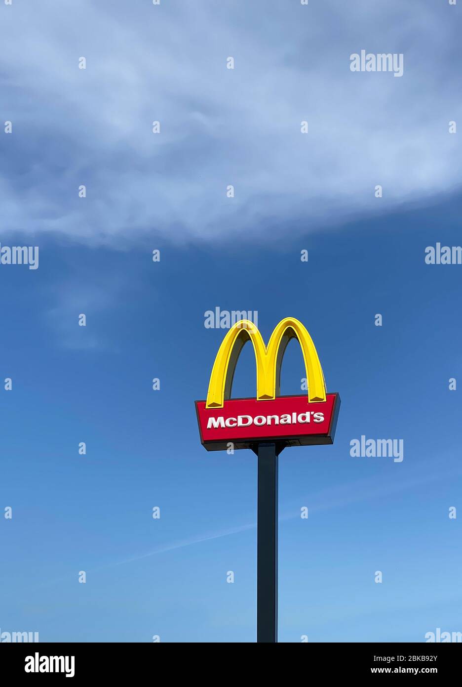 Ashford, Regno Unito - 23 aprile 2020: Primo piano di McDonalds segno all'aperto con la lettera M gialla arrotondata tipica contro il cielo blu. McDonald's è la t Foto Stock