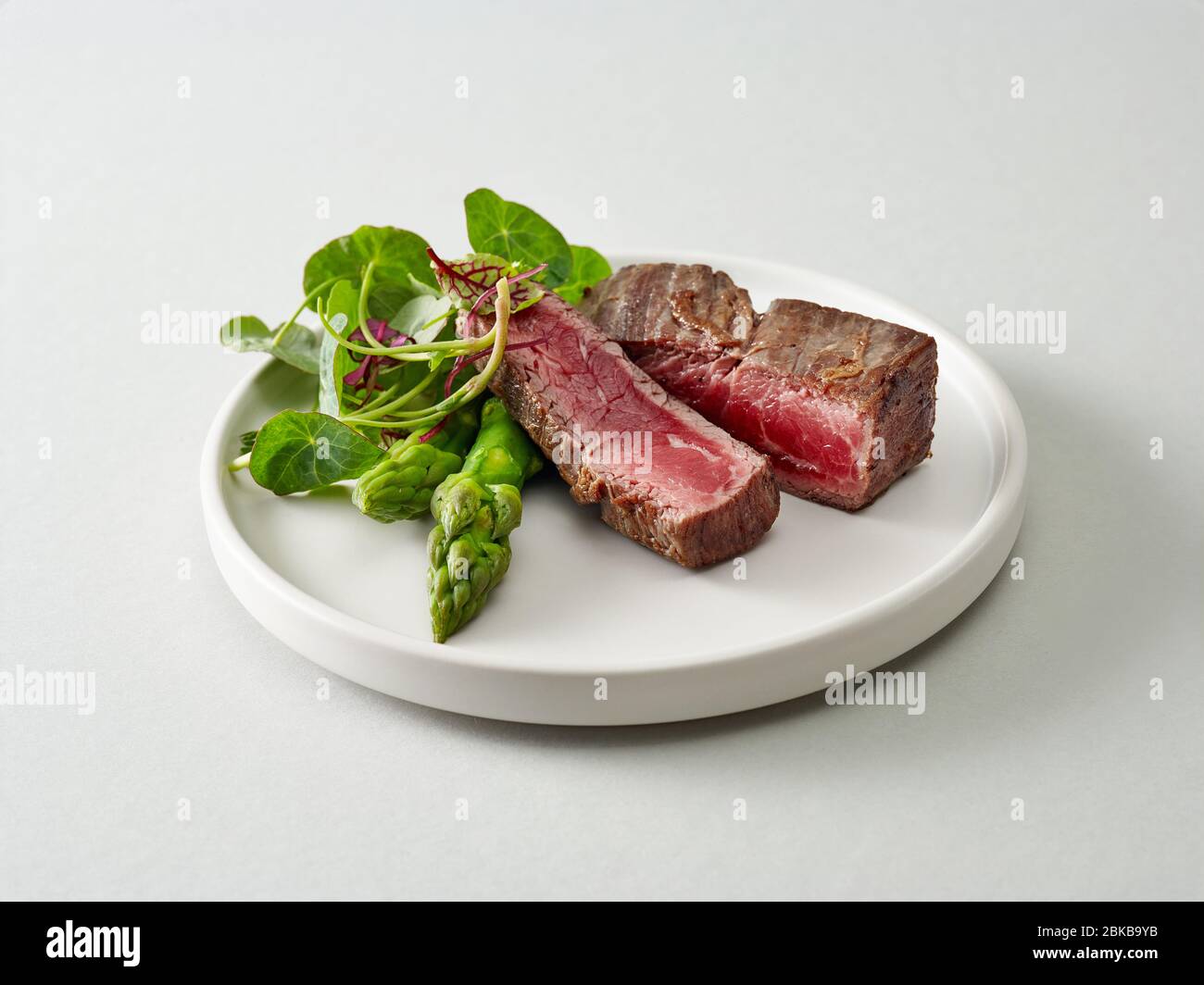 Piatto di carne di manzo wagyu con erbe e asparagi su sfondo grigio chiaro Foto Stock
