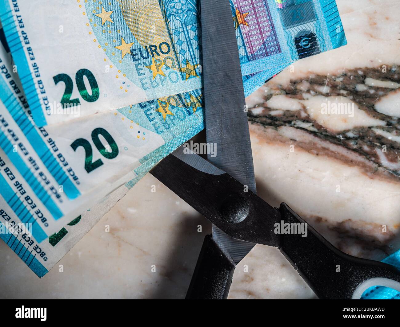 Riduzione delle emissioni e del debito evitando la perdita di valore. Euro moneta moneta inserita in un paio di forbici Foto Stock