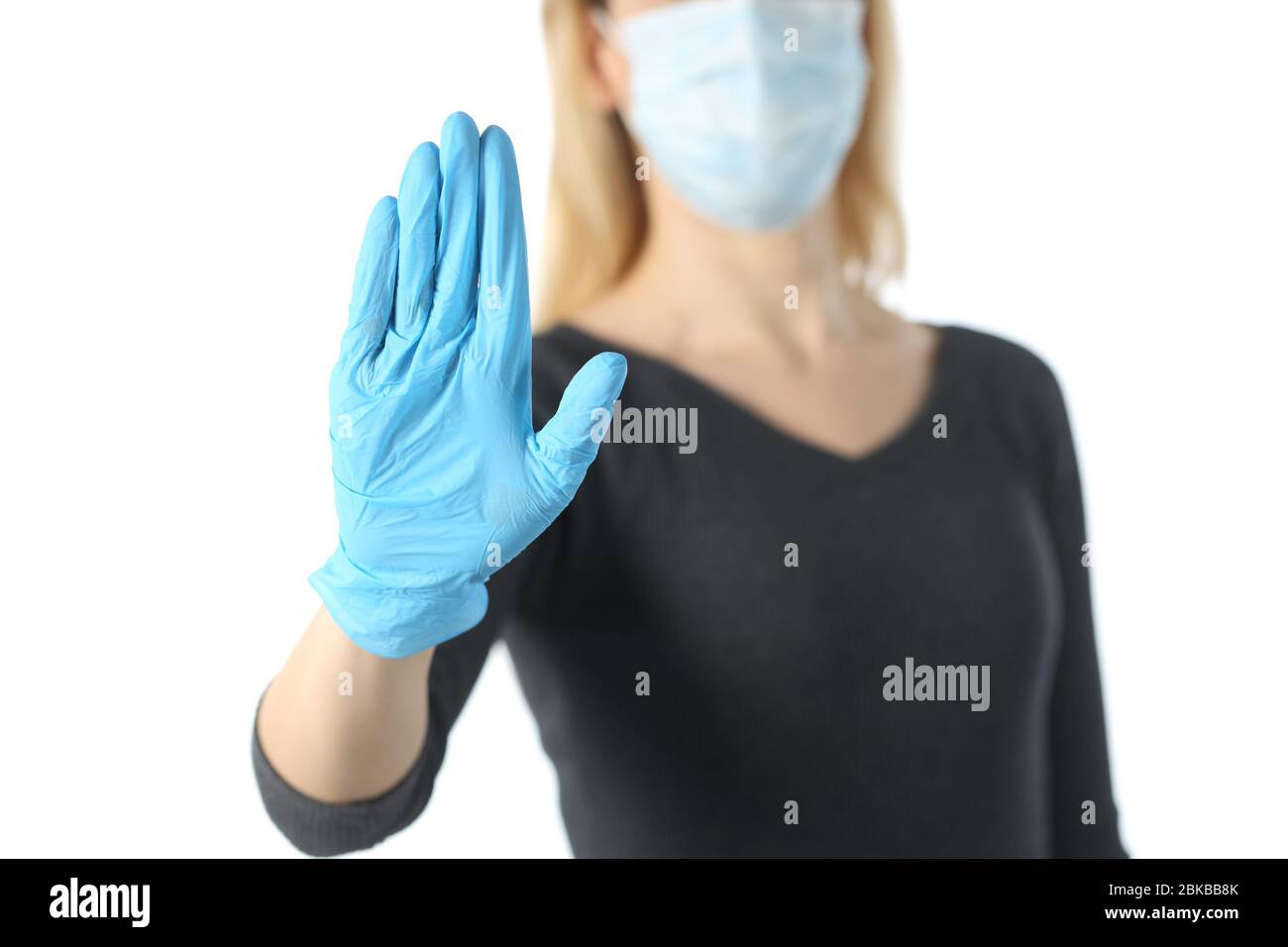 Primo piano della mano ragazza di gesturing stop evitando coronavirus con maschera e guanti isolati su sfondo bianco Foto Stock