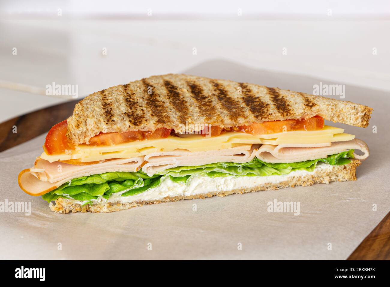 Sandwich Club su carta bianca su tagliere in legno. Pranzo, colazione Foto Stock