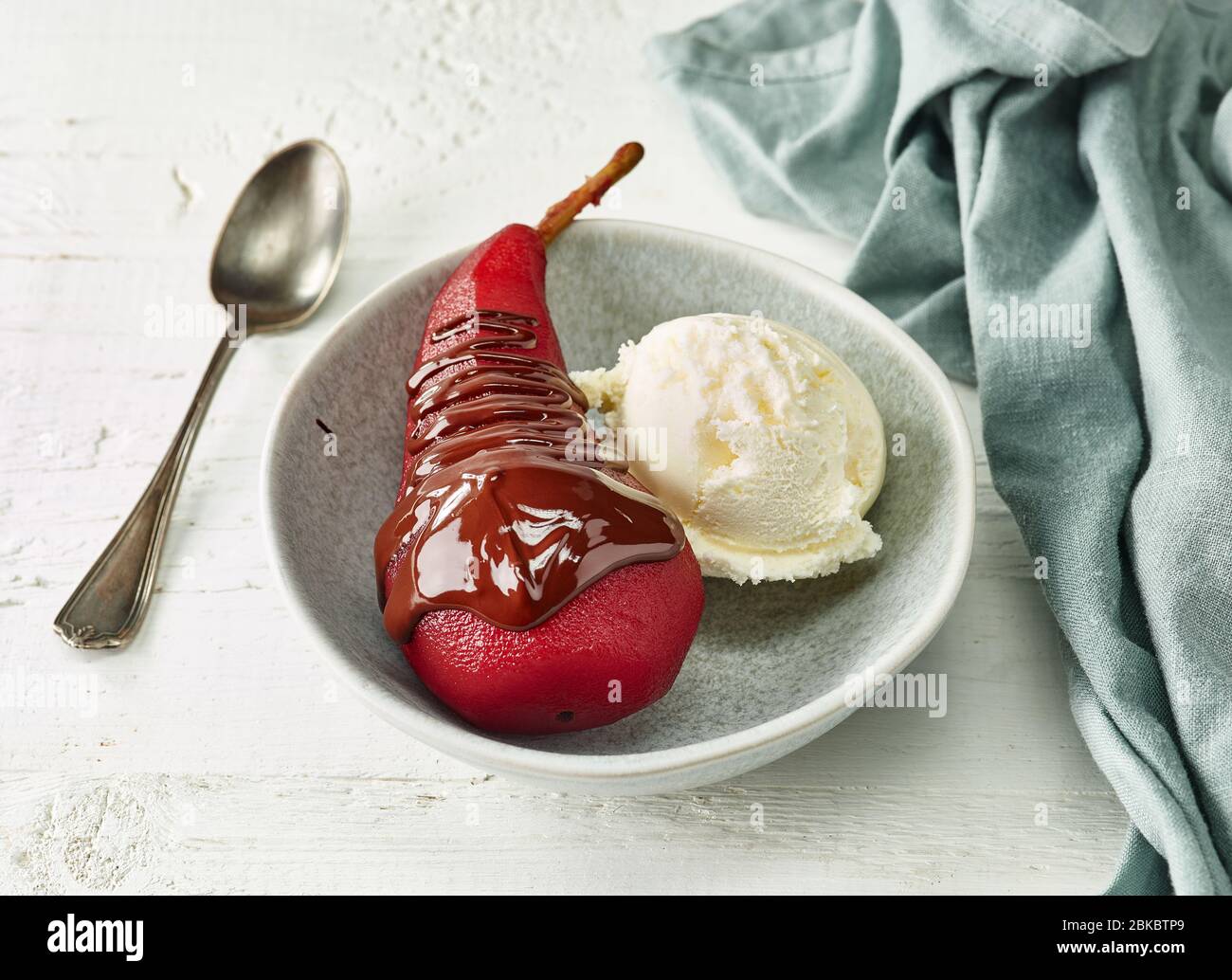 Pera in camicia al vino rosso, dessert decorato con gelato e cioccolato fuso Foto Stock