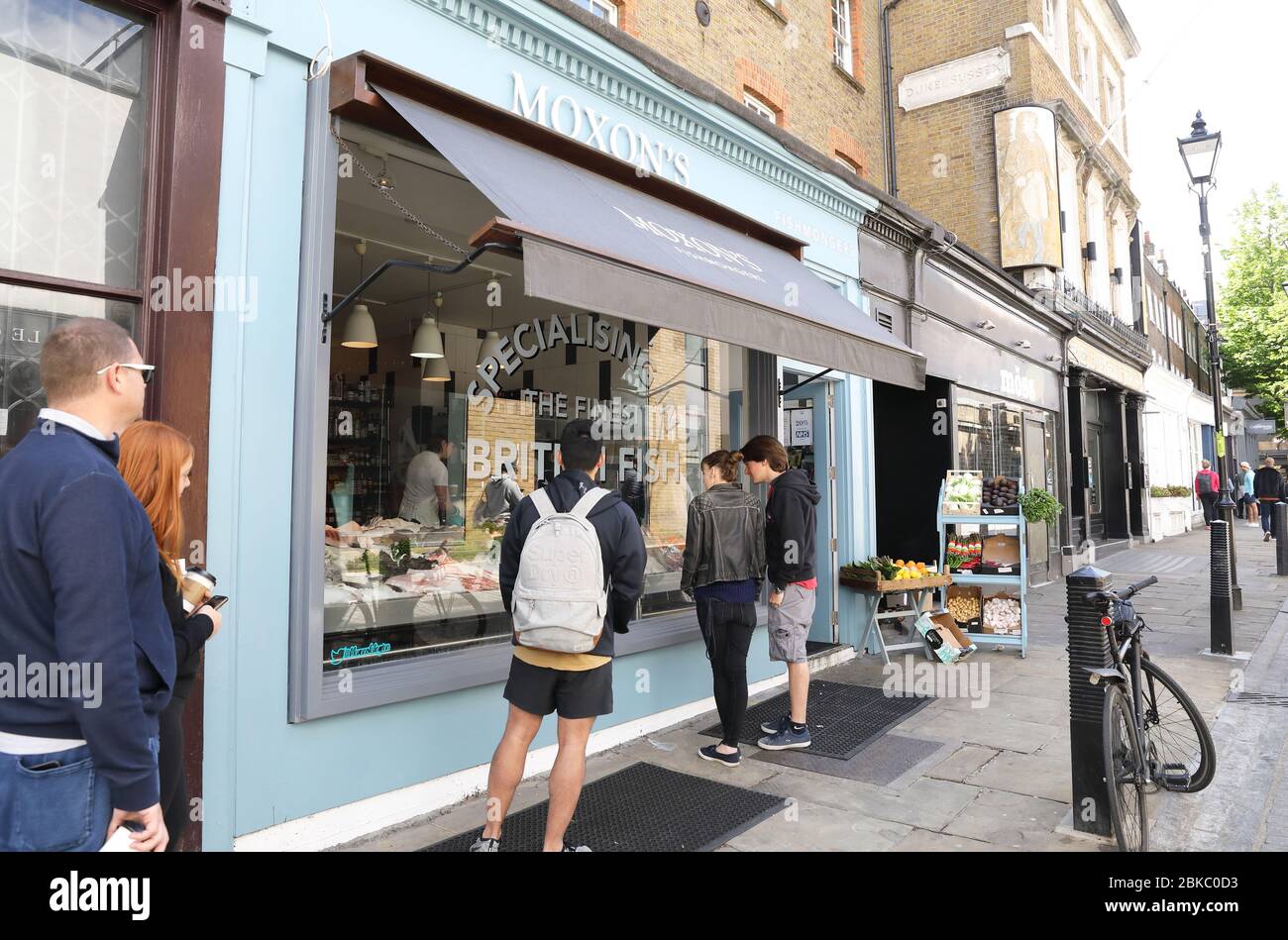 Coda socialmente lontana al di fuori dei pescatori di Moxon sul Camden Passage, a Islington durante il blocco pandemico del coronavirus, Regno Unito Foto Stock