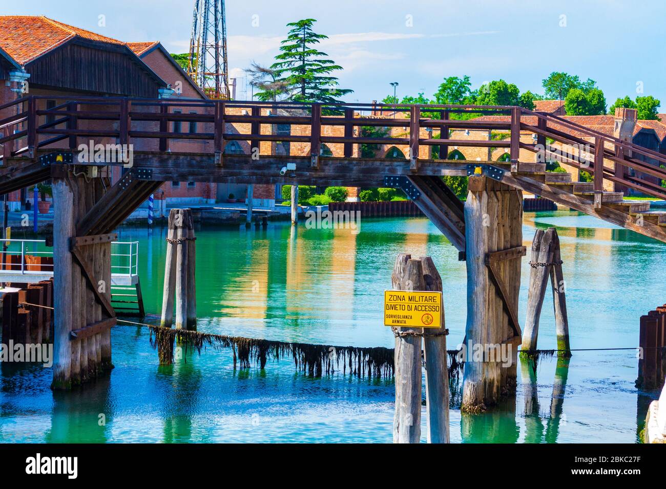 Vecchio ponte in legno sul Rio del Arsenale canale zona militare segni all'ingresso dell'ex Arsenale veneziano nel quartiere di Castello in bella giornata estiva Foto Stock