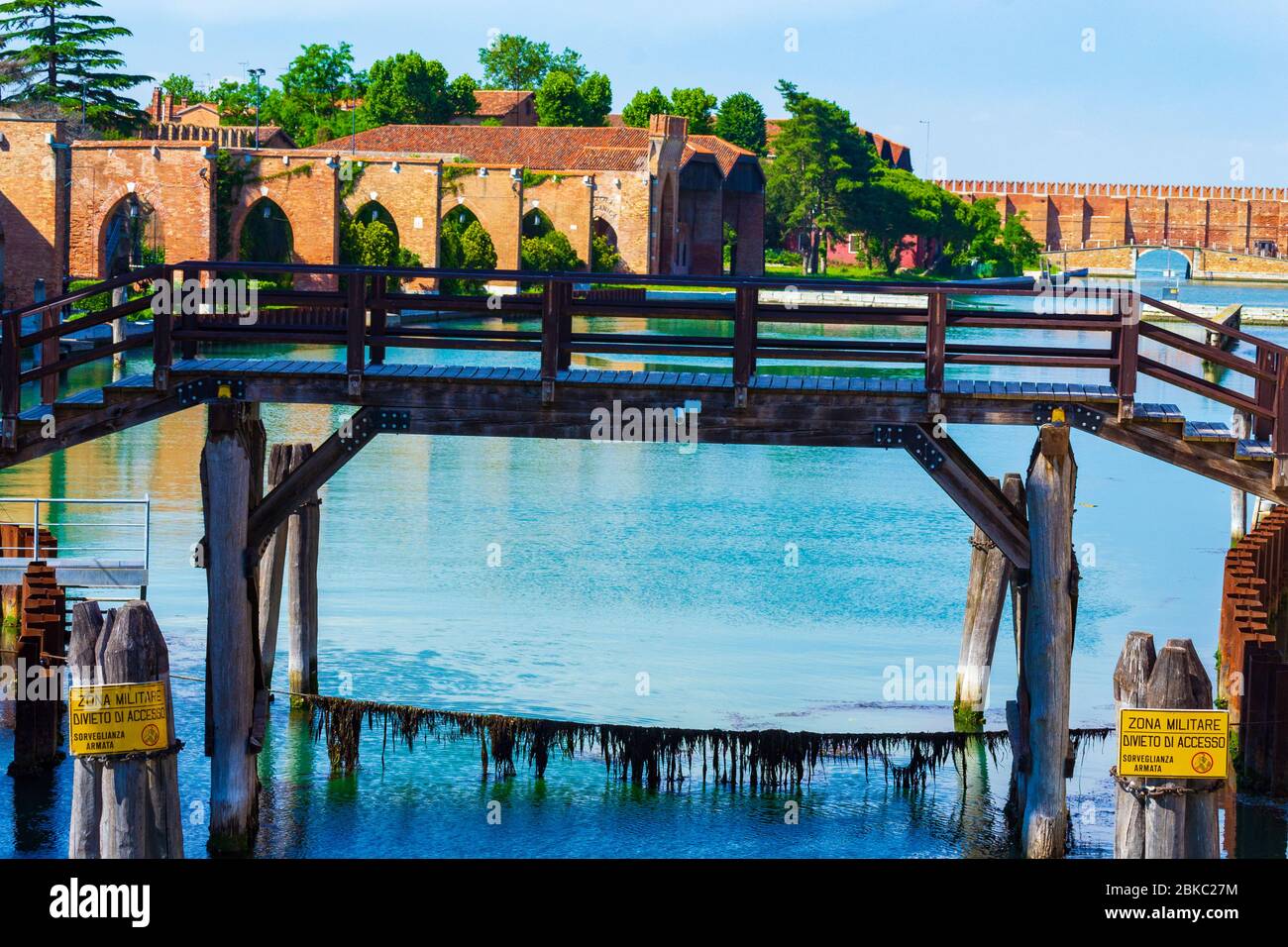 Vecchio ponte in legno sul Rio del Arsenale canale zona militare segni all'ingresso dell'ex Arsenale veneziano nel quartiere di Castello in bella giornata estiva Foto Stock