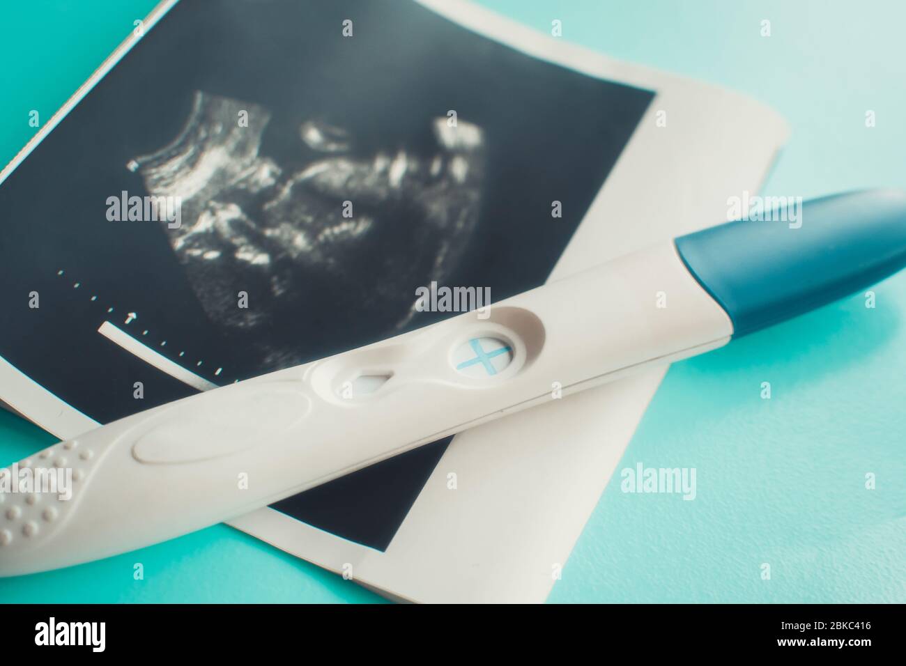 Ecografia con test di gravidanza positivo su sfondo blu. Messa a fuoco selettiva Foto Stock