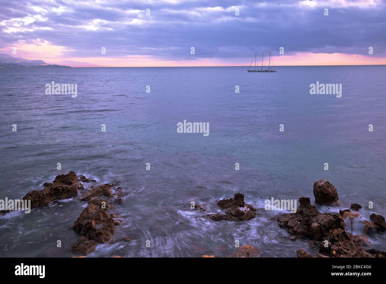 Barca a vela sulla costa della costa Azzurra con vista sul tramonto. Città di Antibes lungomare. Francia. Foto Stock