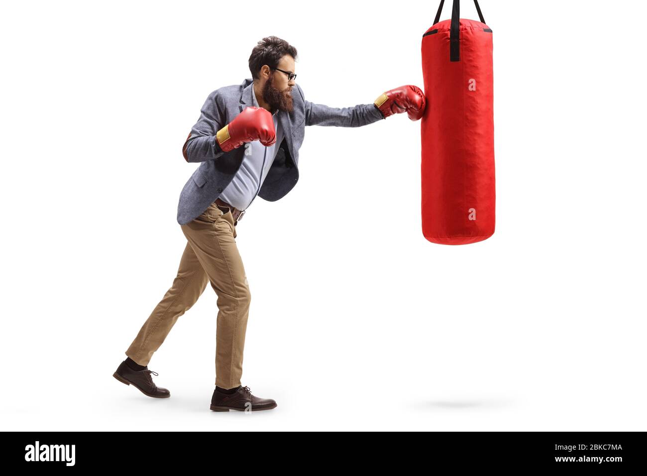 Scatto a tutta lunghezza di un uomo in abiti formali punzonando una borsa da boxe isolato su sfondo bianco Foto Stock