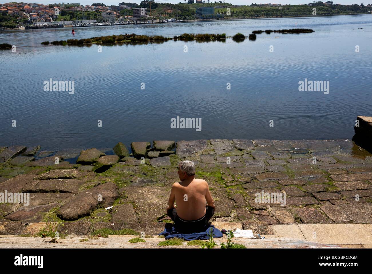 Un uomo è visto prendere il sole il primo giorno dello stato di calamità a causa della pandemia Covid-19 il 3 maggio del 2020 a Porto, Portogallo. Foto Stock