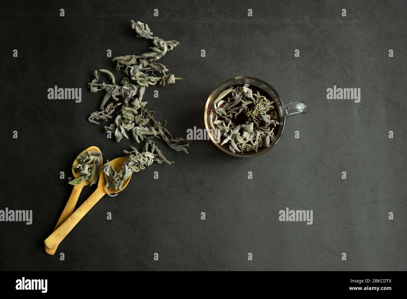 Foglie di salvia asciutte e tè su fondo di pietra. Ingredienti aromatici del tè. Vista dall'alto, piatto, vita still. Foto Stock