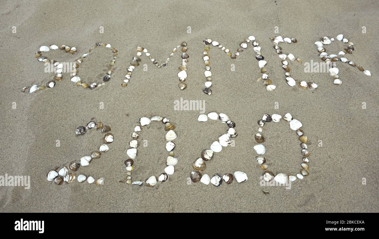 Estate 2020, parola tedesca con conchiglie scritte sulla spiaggia. (Sommer 2020) Foto Stock