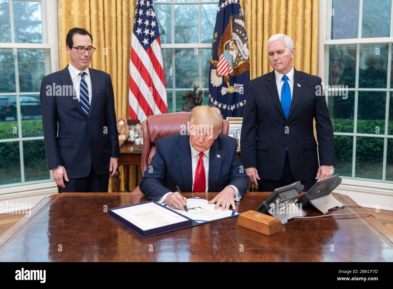 Il presidente Donald J. Trump è Unito dal vice presidente Mike Pence e dal segretario del Tesoro Steven Mnuchin mentre firma S.R. 6201, la prima legge di risposta di Coronavirus delle famiglie, mercoledì 18 marzo 2020, nell'ufficio ovale della Casa Bianca. Il presidente Trump firma il primo Coronavirus Response Act per le famiglie Foto Stock