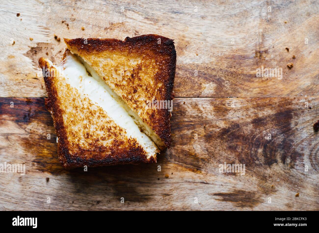 Pane tostato a fette con mozzarella fusa su tagliere in legno Foto Stock
