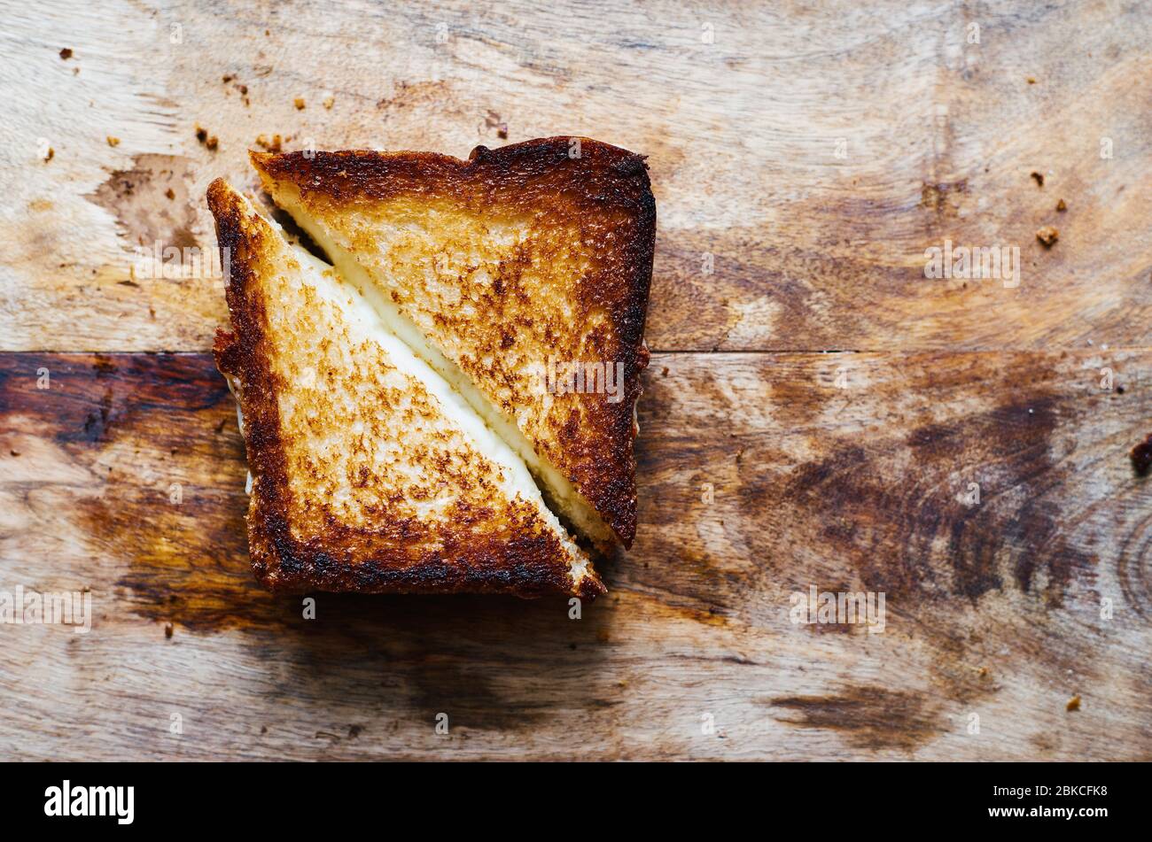 Pane tostato caldo a fette con mozzarella fusa su un tagliere in legno per il testo Foto Stock