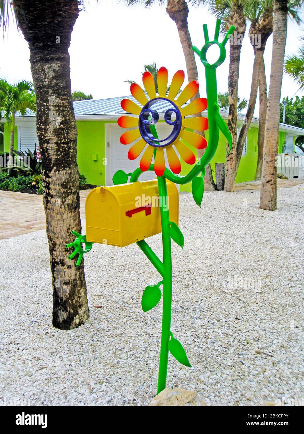 Una casella postale degli Stati Uniti che è tenuta da un fiore smiley-faccia artisticamente fatto di metallo dipinto brillantemente cattura l'occhio della gente che passa da questa casa colorata su Casey Key nella contea di Sarasota lungo la costa del Golfo della Florida, Stati Uniti. È il lavoro creativo di Floridian Scott Gerber, che ha realizzato la sua prima figura sorridente del bastone da tubi di alluminio di scarto nel 2010. Da allora la sua azienda Tube Dude ha venduto migliaia di sculture stravaganti realizzate su misura in vari disegni a clienti di tutto il mondo. Foto Stock