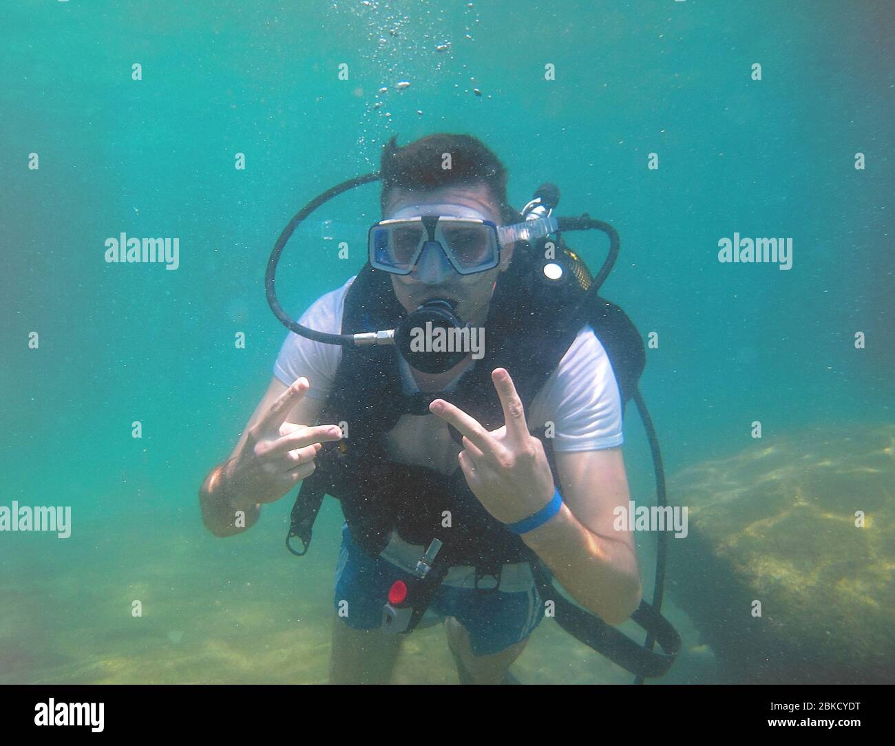 Un ragazzo attrezzato immersioni circondato da molti pesci nelle acque limpide nelle acque blu del Mediterraneo di Antalya. Foto Stock