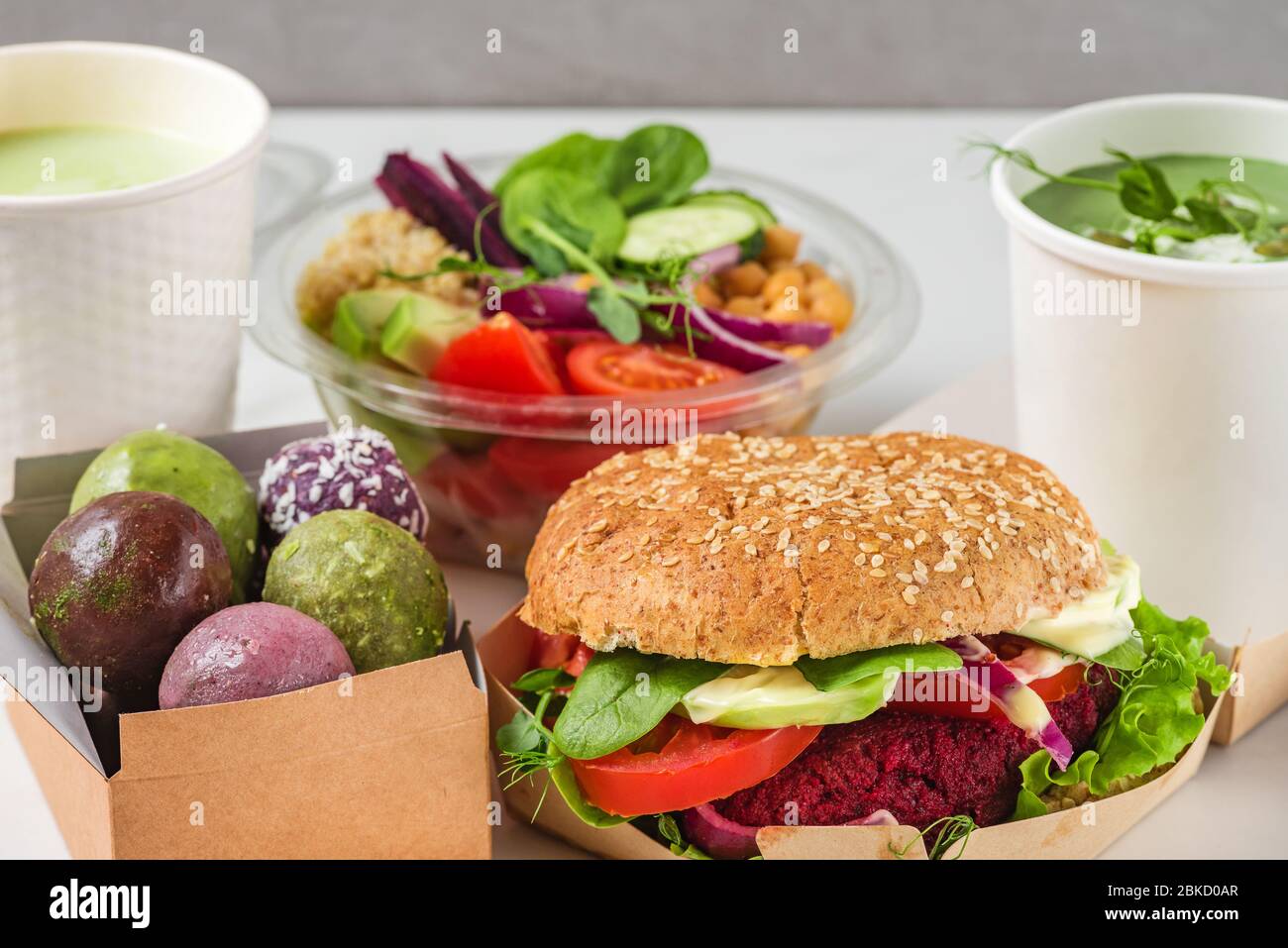 Consegna di cibo da asporto vegano. Set di scatole, contenitori e tazze con cibi e bevande salutari vegani. Menu del ristorante da asporto Foto Stock