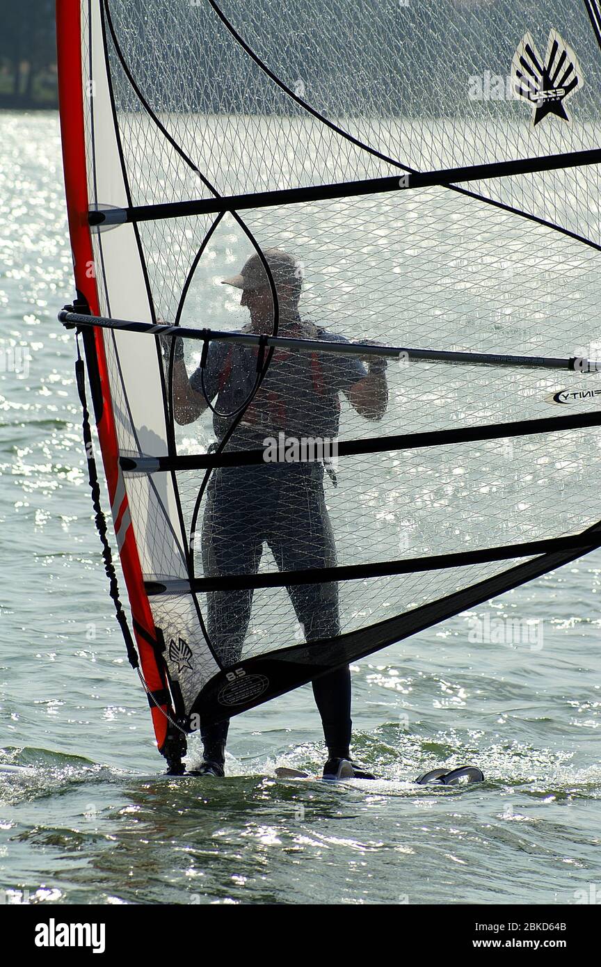 Windsurf sul lago. Uomo windsurf. Windsurfen auf dem Vedi. Ein Mann, der Windsurfen übt. 在湖上滑浪風帆。 一個人練習帆板運動。 Foto Stock