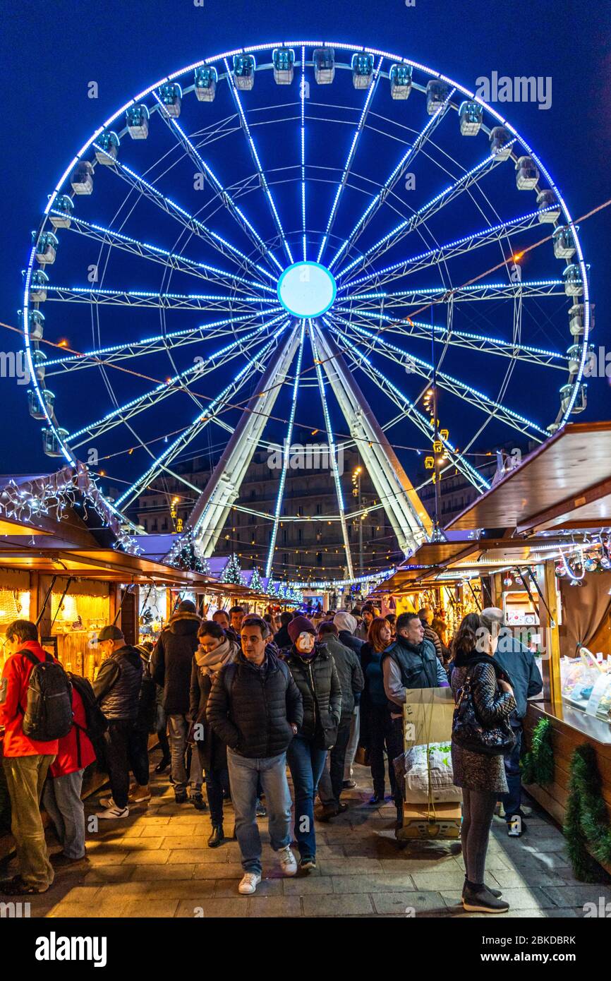 Marsiglia, Francia, 1 gennaio 2020 – gente che fa shopping tra la bancarella del mercato di Natale di Marsiglia con la ruota panoramica sullo sfondo Foto Stock