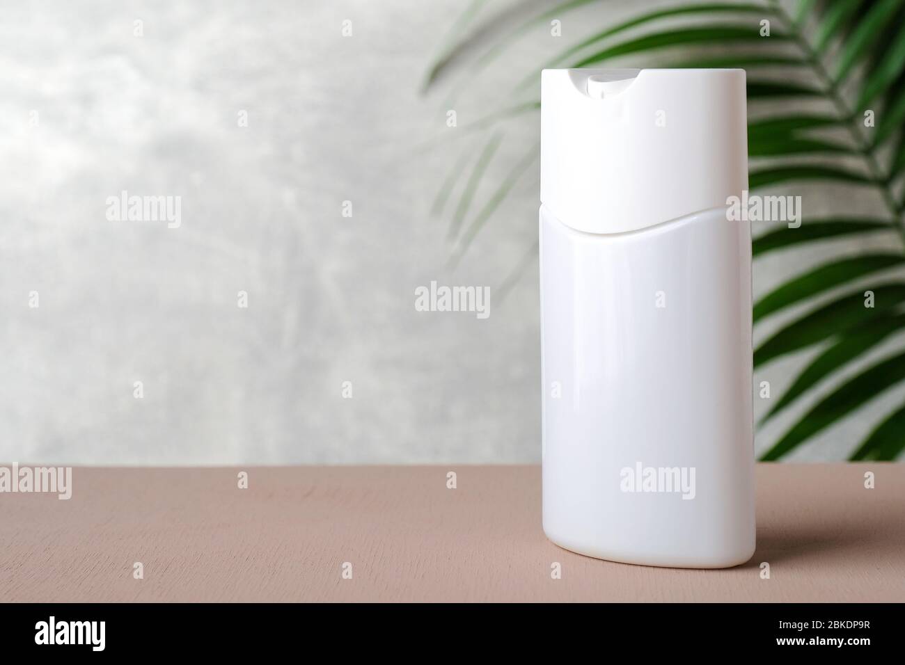 Bottiglia di shampoo vuota con foglia verde tropicale. Mockup di confezionamento cosmetico biologico naturale. Prodotto per la cura dei capelli. Foto Stock