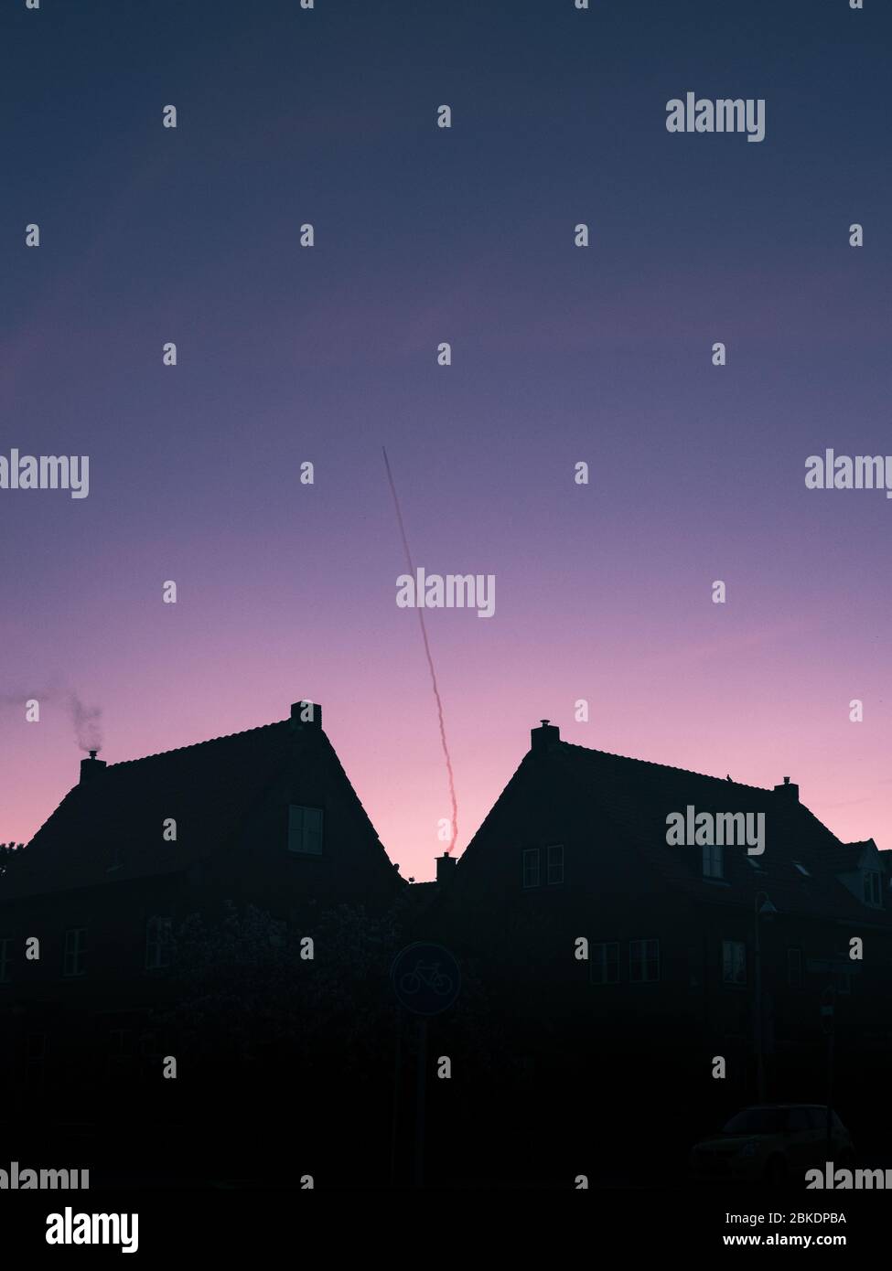 Silhouette nera dei tetti di due case con camini e uno sfondo blu panoramico cielo rosa. L'Aia, Paesi Bassi, Europa. Foto Stock