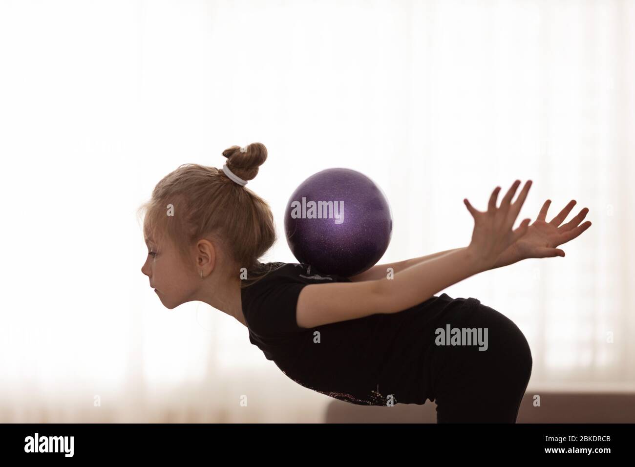 Bella bambina facendo esercizi con una palla fitness. Sport e concetto di stile di vita sano. Foto Stock
