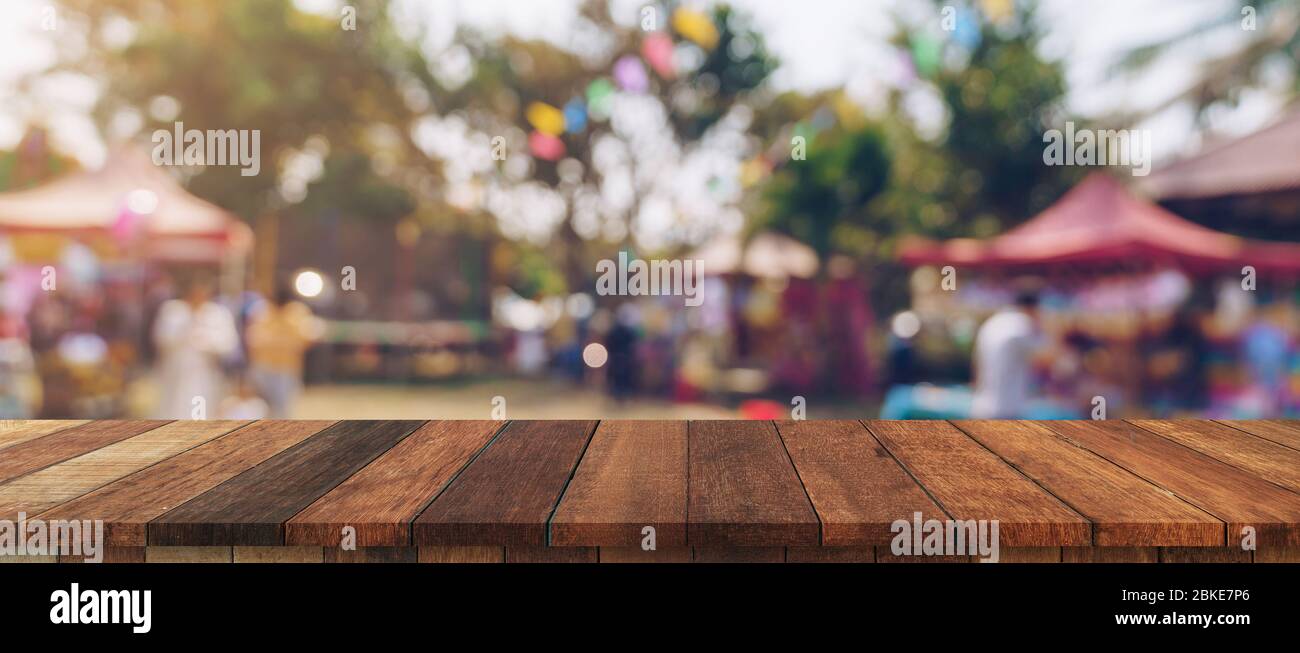 Svuotare tavolo in legno e defocalizzata bokeh di fondo e la sfocatura sullo sfondo di un giardino di alberi nella luce solare, display montage per prodotto. Foto Stock