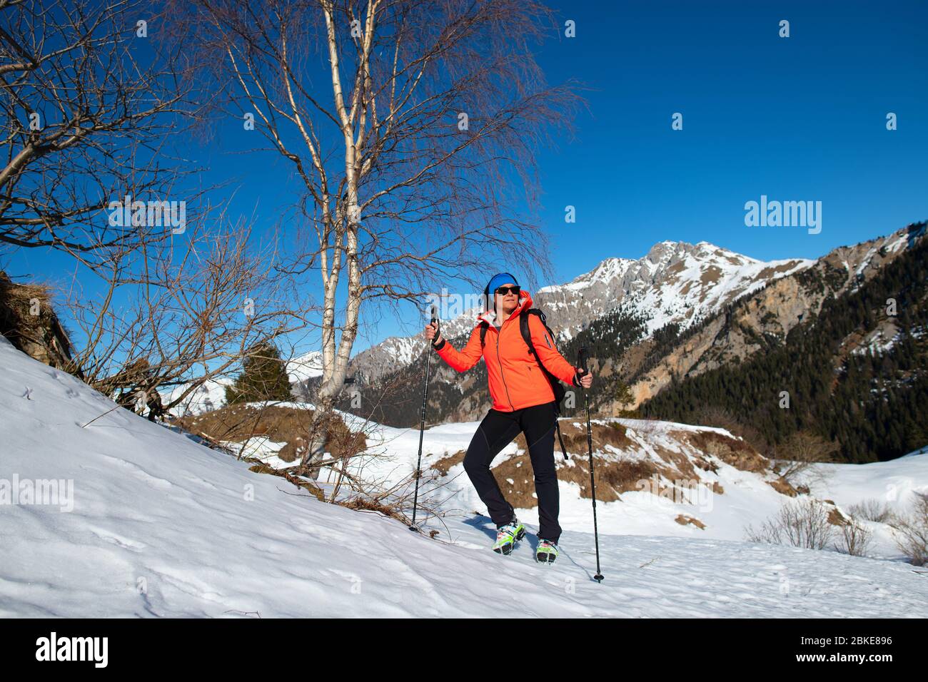 Una donna riposa e guarda la vista durante una passeggiata in montagna sulla neve Foto Stock