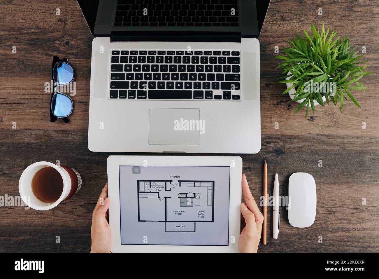 Design che controlla l'appartamento progetto su tablet computer quando si siede alla scrivania dell'ufficio Foto Stock