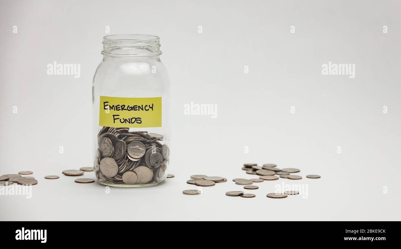 Un vaso di vetro contiene molti quarti, dime e nickels per un'emergenza. Foto Stock
