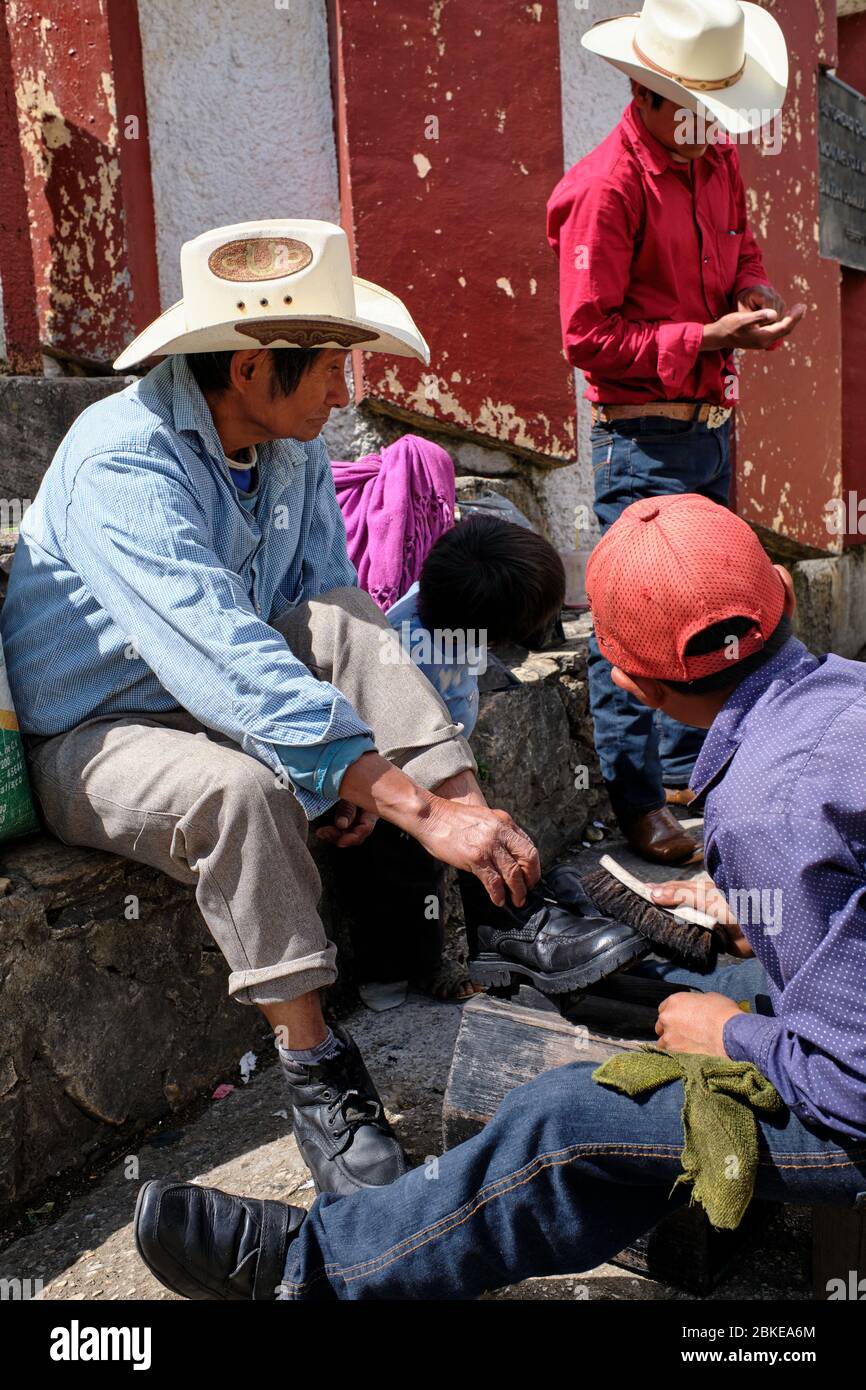 Shoe Shine boy pulendo le scarpe di un uomo con un cappello da cowboy in  Plaza de San Juan Chamula Foto stock - Alamy