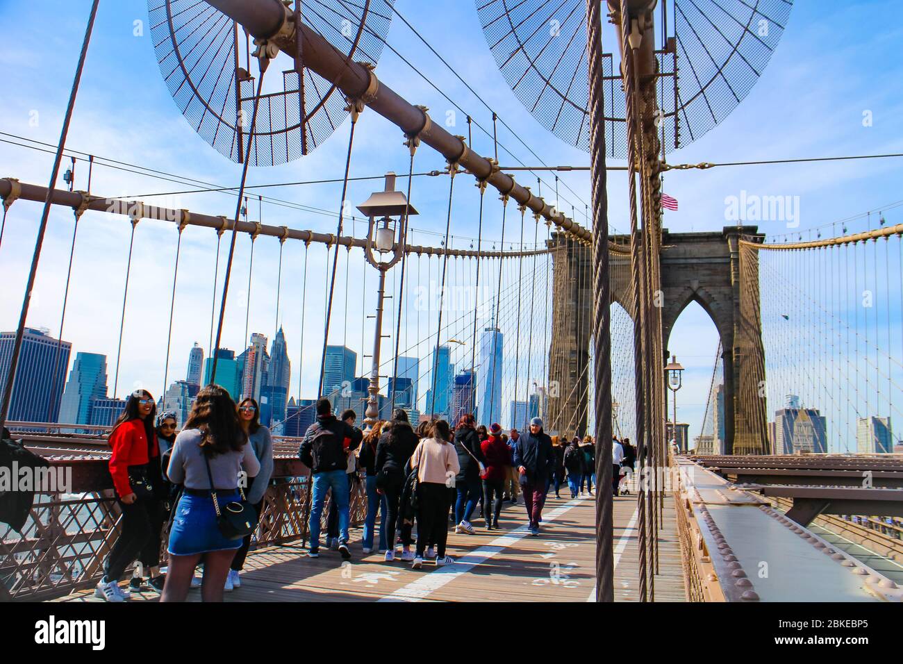 Attraversando il Ponte di Brooklyn con i turisti e una vista dello skyline di Lower Manhattan con il One World Trade Center. Foto Stock