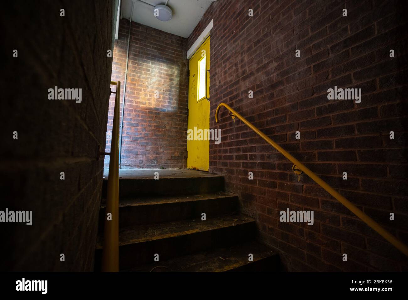 Scala urbana scura e non illuminata, con porta gialla. Foto Stock