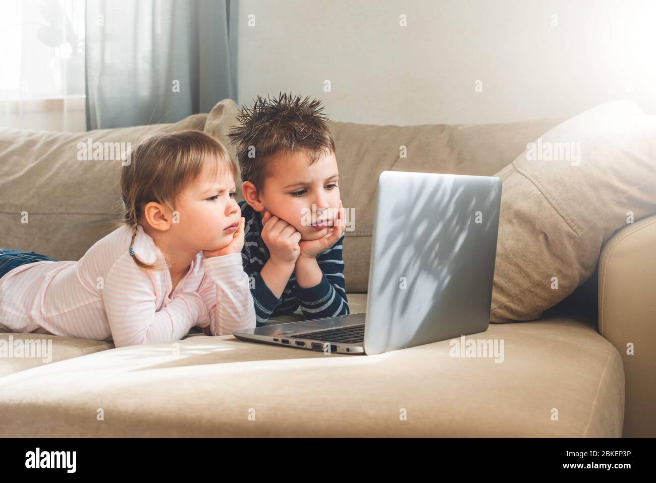 Bambini che studiano a casa utilizzando lezioni online su laptop. Bambini che guardano i cartoni animati online. Quarantena a casa. Formazione a distanza, formazione online. Foto Stock