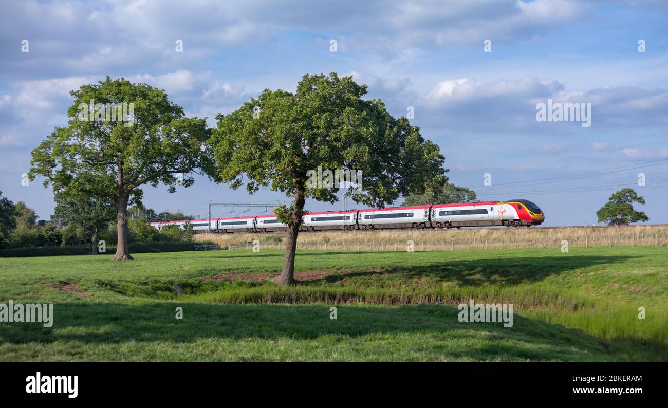 Virgin Trains Alstom pendolino treno che passa attraverso la campagna di Cheshire vicino a Winsford sulla linea principale della costa occidentale Foto Stock